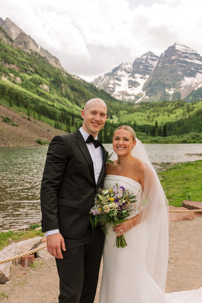 Couple standing on lakeshore with Maroon Bells